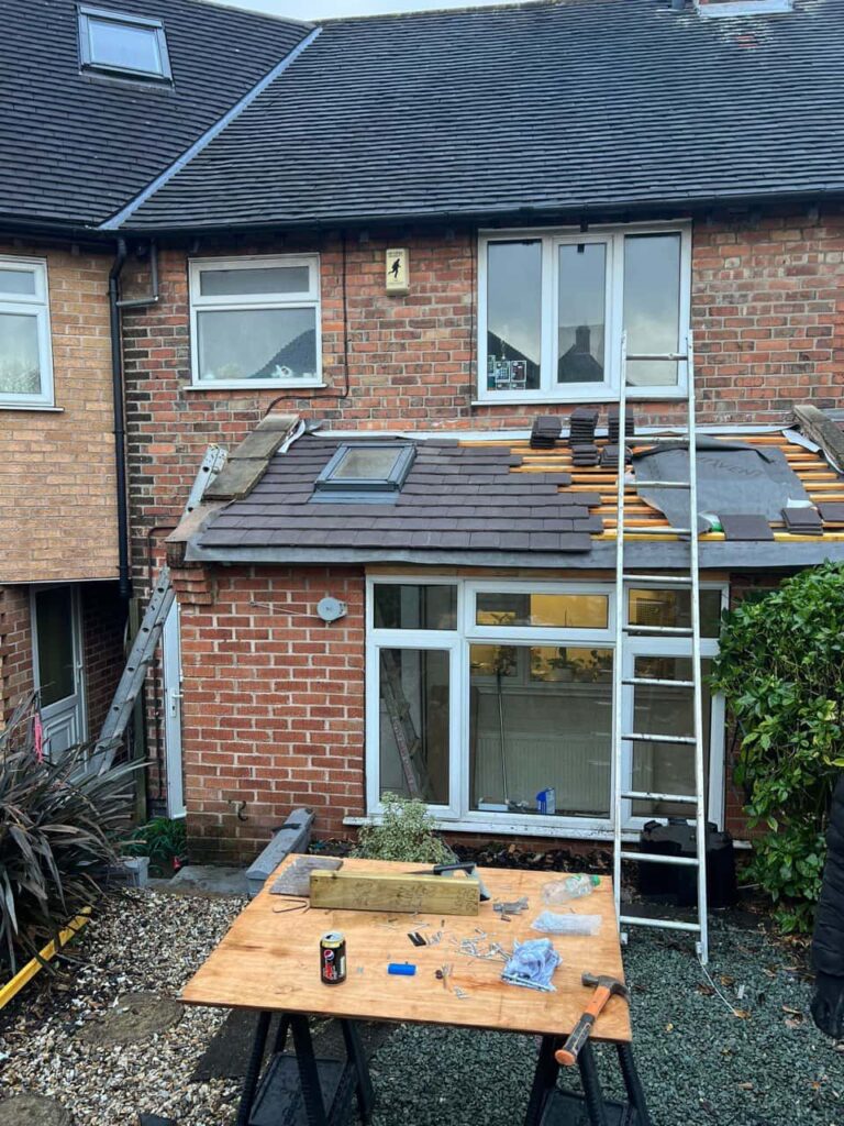 This is a photo of a roof extension that is having new roof tiles installed. This is a photo taken from the roof ridge looking down a tiled pitched roof on to a flat roof. Works carried out by Brownsover Roofing Repairs